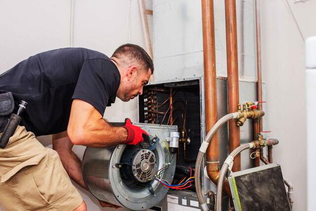 HVAC technician repairing an indoor heating and cooling system